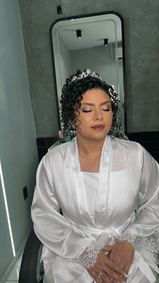 Noiva de cabelo cacheado com tiara, penteado e make da equipe